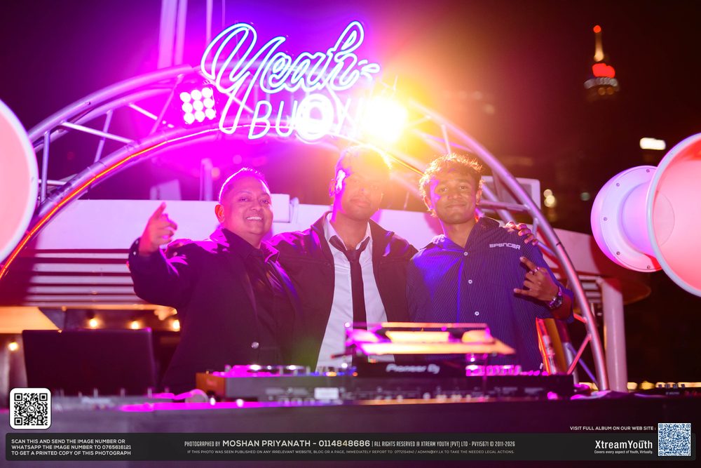 The DJs together at the booth under the pink lit arch.