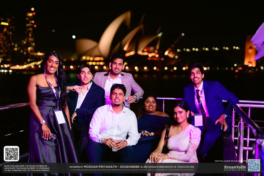 Friends leaning on the deck rail, harbour lights over their shoulders.