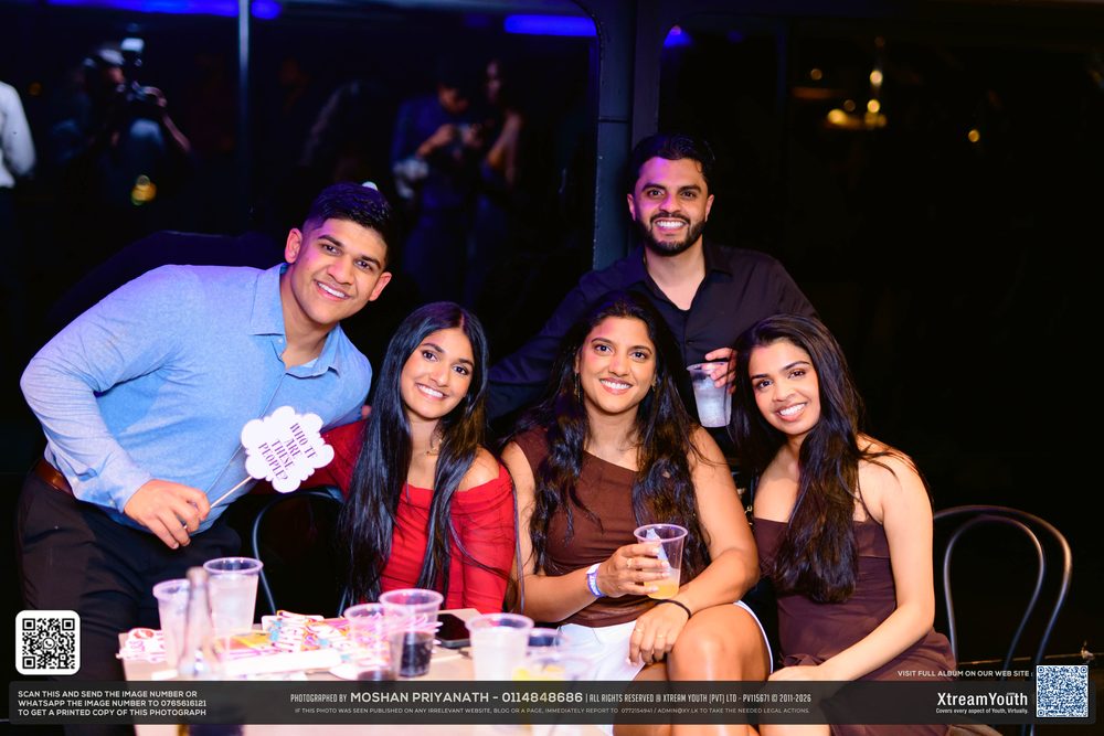 Five friends squeezed around a booth table, drinks in front of them.