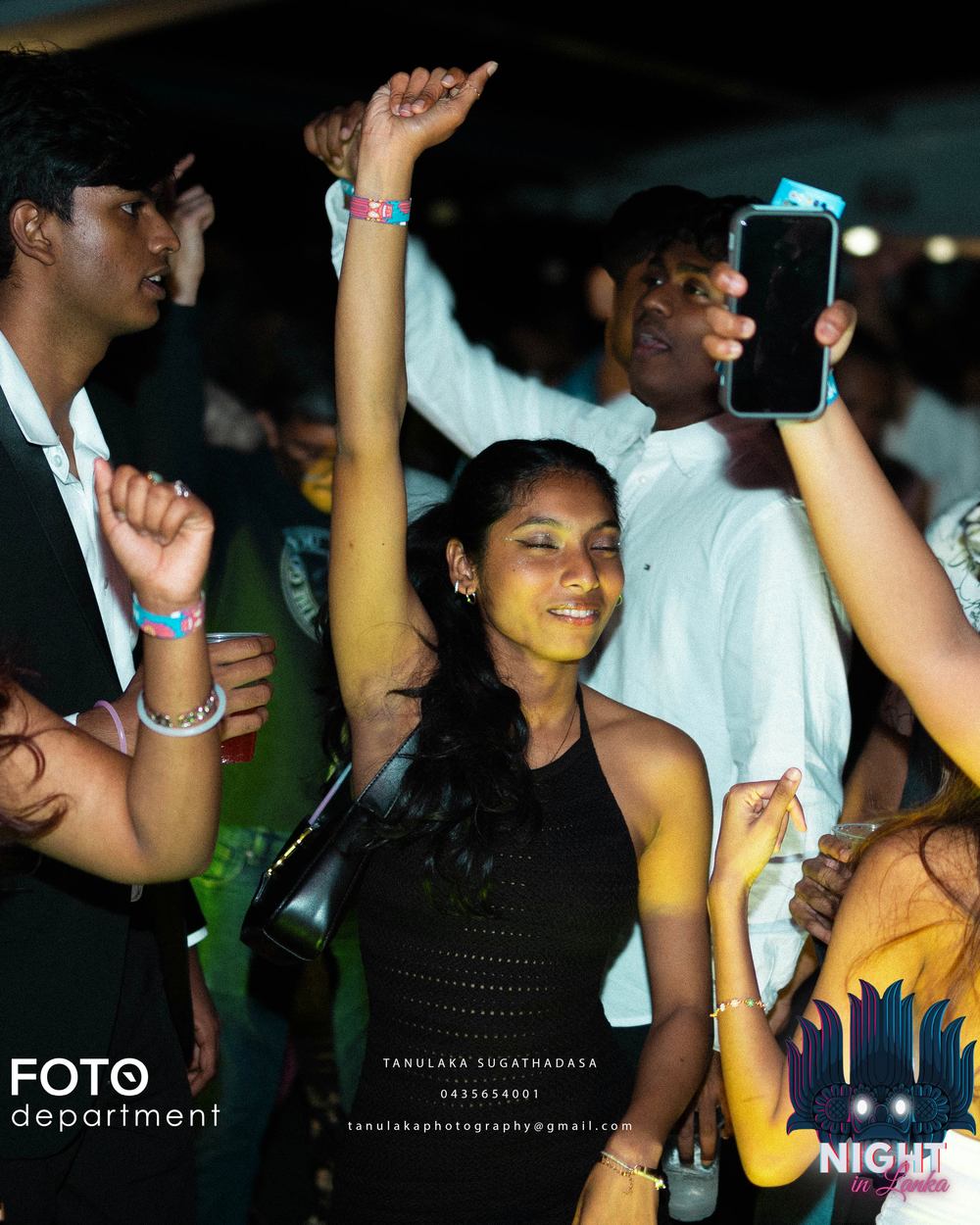 The crowd with hands in the air under pink light.